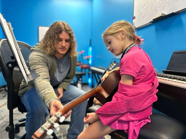 A BLE guitar teacher working one-on-one with a young musician